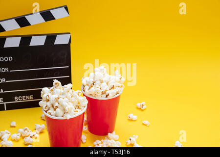 Kino film für Zwei. Frische salzige Pop Corn und Movie clapper Board, Gelb Farbe Hintergrund, kopieren Raum Stockfoto
