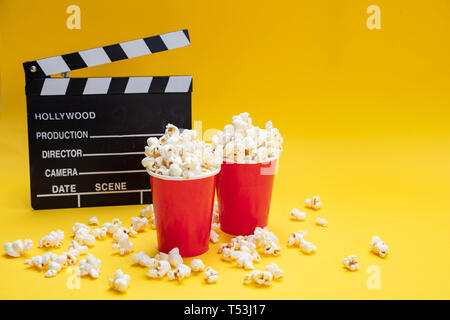 Kino film für Zwei. Frische salzige Pop Corn und Movie clapper Board, Gelb Farbe Hintergrund, kopieren Raum Stockfoto