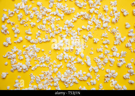 Frische salzige Popcorn auf Gelb Farbe Hintergrund verstreut, Vollbild, Ansicht von oben Stockfoto