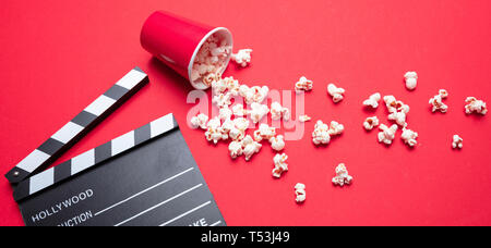 Kino film Konzept. Frische salzige Pop Corn und Movie clapper Board, rote Farbe Hintergrund, Banner Stockfoto