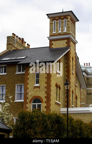 Brick House mit weißen Fenstern und einem Turm in einer ruhigen Gegend im Zentrum von London. Strassenleuchte, blühenden Bäumen. Stockfoto