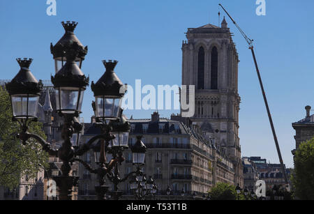 Die Türme der Kathedrale von Notre Dame ater Feuer mit riesigen Kran in der Nähe. Die Lampe Beiträge von Hotel de Ville Platz im Vordergrund. Paris. Stockfoto