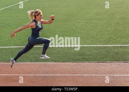 Junge Frau auf Stadion sportlicher Lifestyle auf Track konzentriert Seitenansicht Stockfoto