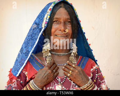 Ältere indische Lambadi Frau (Banjara, Indische gipsy) aus Karnataka birgt in ihrem traditionellen Outfit vor der Kamera und zeigt ihre Silber Schmuck. Stockfoto