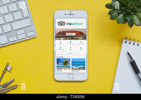 Ein iPhone zeigt die Tripadvisor website ruht auf einem gelben Hintergrund Tabelle mit einer Tastatur, Tasten, Notepad und Anlage (nur redaktionelle Nutzung). Stockfoto