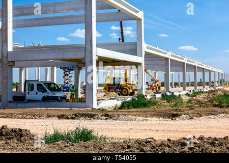 Montage einer riesigen Beton Skelett der industriellen Gebäude mit Maschinen, Menschen arbeiten. Blick auf die Baustelle. Stockfoto