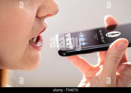 Nahaufnahme einer jungen Frau mit Spracherkennung auf dem Mobiltelefon Stockfoto