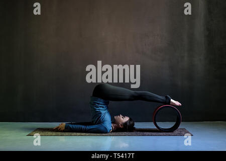 Mädchen in halasana pose Yoga auf schwarzem Hintergrund. Stockfoto