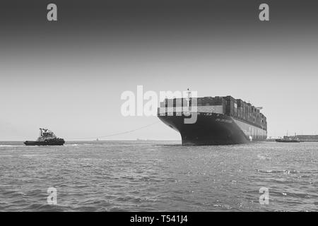 Schwarz-weiß-Foto des Containerschiffs CMA CGM CENTAURUS, das vor dem Anlegen in Long Beach, Kalifornien, USA, von 3 Schleppern um 180 Grad gedreht wurde. Stockfoto