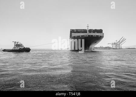 Schwarz-weiß-Foto des Containerschiffs CMA CGM CENTAURUS, das von Tug JOHN QUIGG vor dem Anlegen in Long Beach, USA, um 180 Grad gedreht wurde Stockfoto