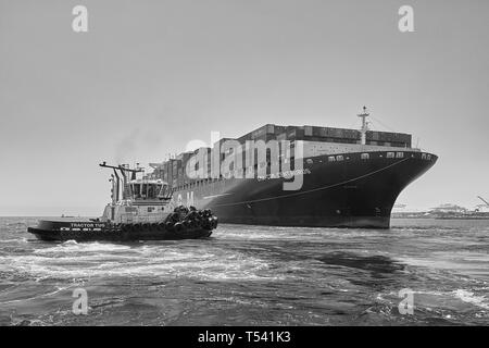 Schwarz-weiß Foto des Containerschiffes, CMA CGM CENTAURUS, um 180 Grad, um Schlepper John QUIGG gedreht, Vor dem Andocken in Long Beach, USA. Stockfoto