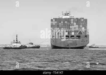 Schwarz-weiß-Foto des Containerschiffs CMA CGM CENTAURUS, das vor dem Anlegen in Long Beach, Kalifornien, USA, von 3 Schleppern um 180 Grad gedreht wurde. Stockfoto