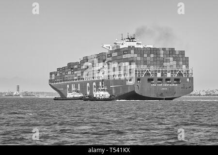 Schwarz-weiß-Foto des Containerschiffs CMA CGM CENTAURUS, das vor dem Anlegen in Long Beach, Kalifornien, USA, von zwei Schleppern um 180 Grad gedreht wurde Stockfoto