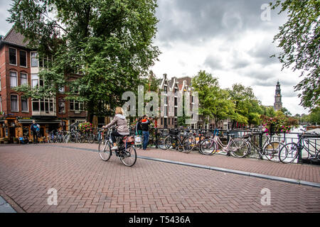 AMSTERDAM, NIEDERLANDE - 31 AUGUST, 2018: Blick entlang Kanal von Amsterdam gesehen mit Brücke und Fahrräder im Blick. Stockfoto