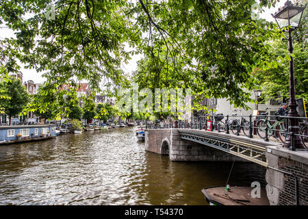 AMSTERDAM, NIEDERLANDE - 31 AUGUST, 2018: Blick entlang Kanal von Amsterdam gesehen mit Brücke und Fahrräder im Blick. Stockfoto