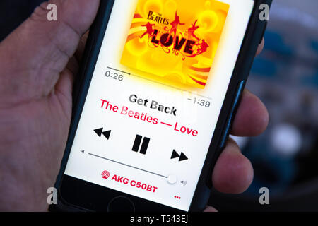 In dieser Fototafel hört sich jemand die Musik des Beatles auf einem Smartphone an. Auf dem Bildschirm werden der Titel des Liedes „Get Back“ und das Cover des al angezeigt Stockfoto