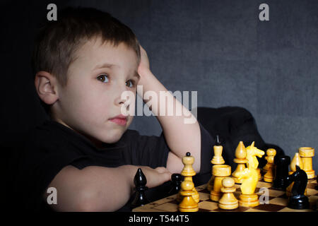 Eine Vorschule Kind spielt Schach. Der kleine Junge ist Denken über Bewegung. Der Kurs des Pferdes. Stockfoto