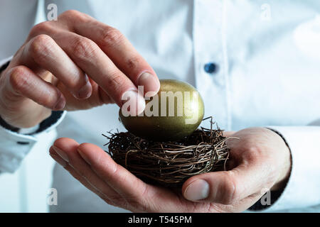 In der Nähe von des Menschen Hand goldene Ei ins Nest Stockfoto