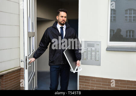 Junge männliche Techniker Öffnen der Tür beim Tragen Desktop in der Hand Stockfoto