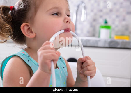 Close-up süsse kleine Mädchen beißen Kabel in Ihrem Mund zu Hause Stockfoto