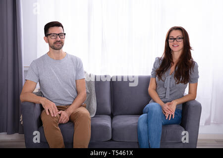 Junges Paar sitzt auf einem Sofa an jedem anderen Suchen Stockfoto