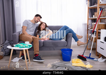 Lächelndes Paar entspannt auf einem Sofa im Wohnzimmer zu Hause unordentlich Stockfoto