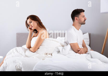 Seitenansicht des Verzweifelten Ehepaar Rücken an Rücken auf dem Bett Stockfoto