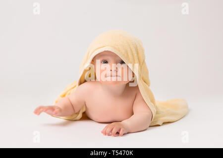 Toddler Boy mit gelben Handtuch auf dem Kopf auf weißem Hintergrund, Porträt von niedlichen Kaukasischen neugeborenes Baby. Das Kind ist in einem gelben weichen Handtuch gewickelt Stockfoto