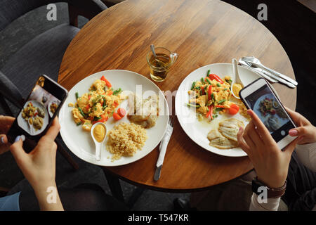 Frauen blogger nimmt Fotos von ihr Essen in einem Cafe mit Handy. Hände mit Bildschirm des Telefons zu schließen. Stockfoto