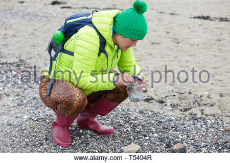 Strand sauber, Freiwillige zu suchen und Sammeln von schädlichen microplastics und Sie in ein Gefäß für die sichere Entsorgung Stockfoto