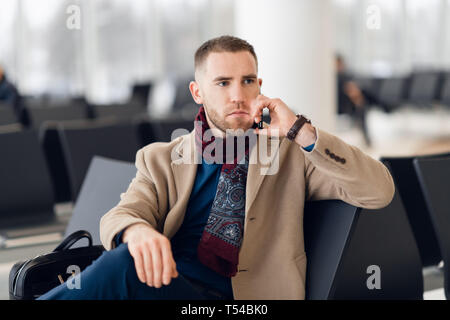 Stattliche hipster moderne Geschäftsmann mit Bart Aufruf auf Handy am Flughafen oder Bürogebäude Stockfoto