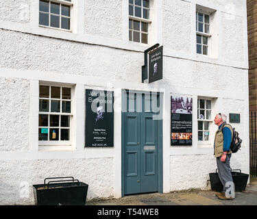 Dunbar, East Lothian, Schottland, Großbritannien. 21. Apr 2019. John Muir's 181st Geburtstag in seinem Geburtsort. Der John Muir Birthplace Museum im Zentrum der Stadt. Ein älterer Mann an der Zeichen auf der Vorderseite des Gebäudes suchen Stockfoto