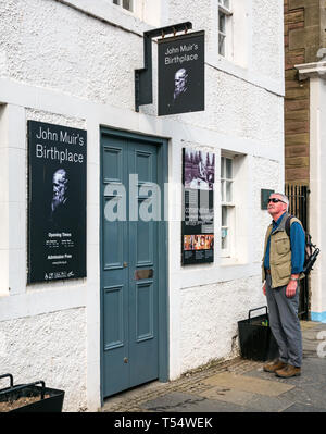 Dunbar, East Lothian, Schottland, Großbritannien. 21. Apr 2019. John Muir's 181st Geburtstag in seinem Geburtsort. Der John Muir Birthplace Museum im Zentrum der Stadt. Ein älterer Mann an der Zeichen auf der Vorderseite des Gebäudes suchen Stockfoto