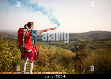 Weibliche Bergsteiger auf Hoch und Senden von Smoke Signal für Wanderer Gruppe Stockfoto