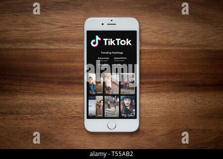 Ein iPhone mit dem Tik Tok Website beruht auf einem einfachen Holztisch (nur redaktionelle Nutzung). Stockfoto