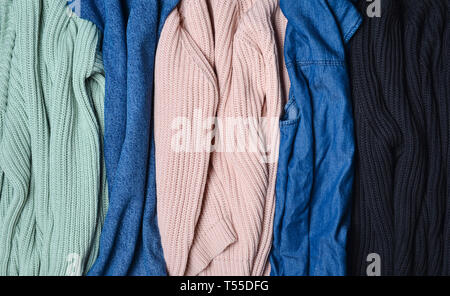 Stapel von gestrickten Pullover und Jeans. Hintergrund der Kleidung. Women's Kleiderschrank. Stockfoto