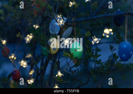Ostern Eier hängen von einem Baum und sind indirekt mit einer Lichterkette beleuchtet Stockfoto