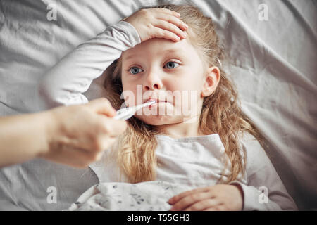 Fürsorgliche Mutter misst die Temperatur eines kranken Mädchen Stockfoto