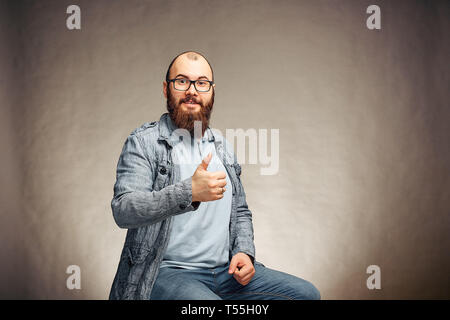 Ein bärtiger Mann in Gläsern mit Daumen hoch , emotionen Stockfoto