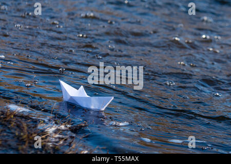 Ein Papier Boot auf eine turbulente Strom von Wasser kämpft mit der Strömung. Kleines Papier Boot fließt entlang des Flusses Stockfoto