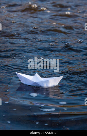 Ein Papier Boot auf eine turbulente Strom von Wasser kämpft mit der Strömung. Kleines Papier Boot fließt entlang des Flusses Stockfoto