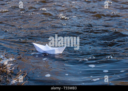 Ein Papier Boot auf eine turbulente Strom von Wasser kämpft mit der Strömung. Kleines Papier Boot fließt entlang des Flusses Stockfoto