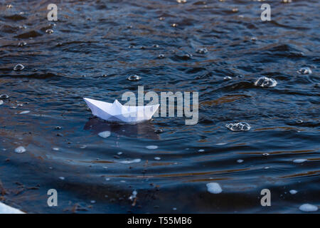 Ein Papier Boot auf eine turbulente Strom von Wasser kämpft mit der Strömung. Kleines Papier Boot fließt entlang des Flusses Stockfoto