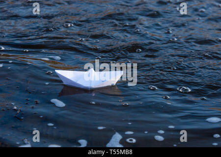 Ein Papier Boot auf eine turbulente Strom von Wasser kämpft mit der Strömung. Kleines Papier Boot fließt entlang des Flusses Stockfoto