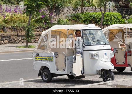 FUNCHAL, Madeira, Portugal - 22 Juli, 2018: Der Fahrer des touristischen Elektrofahrzeug begrüßt Kunden auf der Funchal Waterfront. Autos geparkt sind o Stockfoto