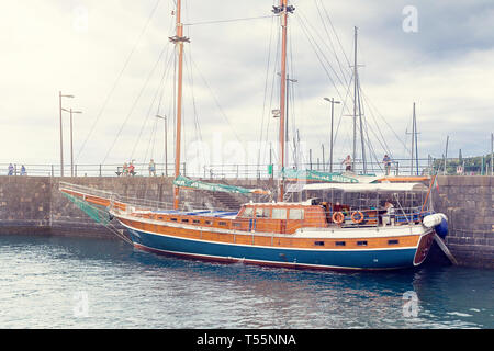 FUNCHAL, Madeira, Portugal - 22 JULI 2018: Sightseeing Tour Boot am Pier in Funchal. Ein Schiff mit deflationiert Segel an der Pier an einem bewölkten Sommer da Stockfoto