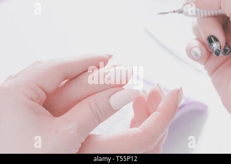Die Hände des Meisters der Maniküre und die Hände des Client close-up Während der Nail Design Prozess. Vorbereitung für das Lackieren mit speziellen wählen Stockfoto