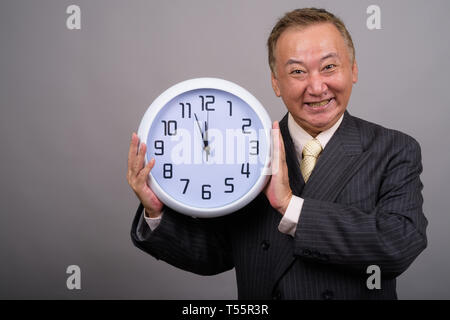 Portrait von Reifen asiatische Geschäftsmann gegen grauer Hintergrund Stockfoto