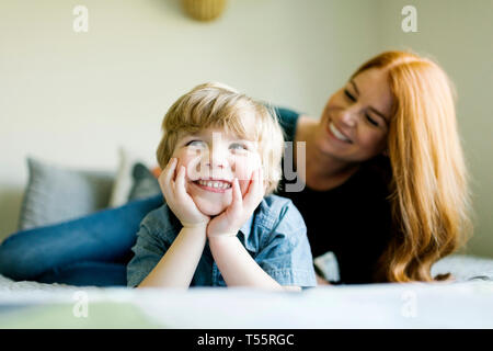 Lächelnde Mutter und Sohn liegend auf Bett Stockfoto