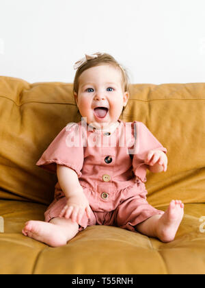 Baby Mädchen mit rosa Outfit auf dem Sofa Stockfoto